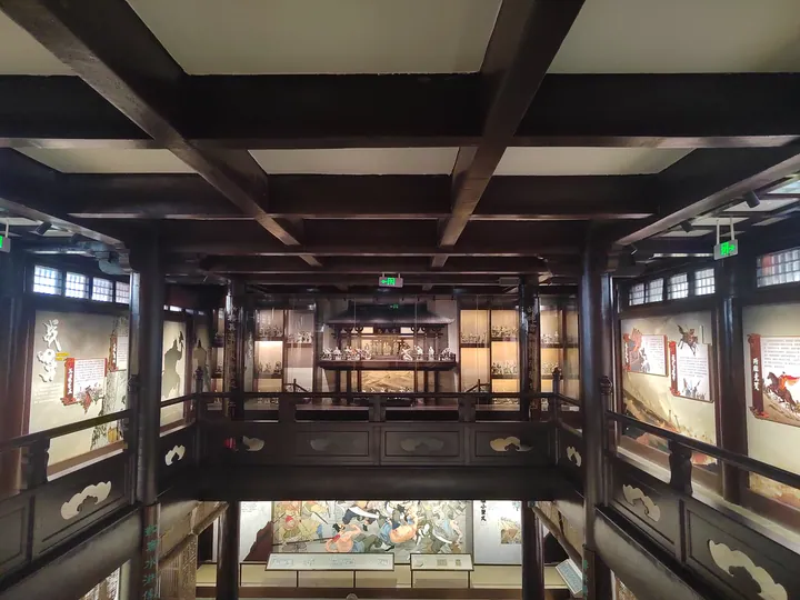 Dark wooden multi-level interior hall with balconies and painted murals on the walls.