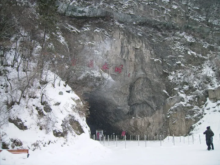 Snow-covered rock entrance to Benxi Water Cave with its name painted in red
