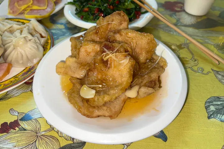Plate of crispy fried pork strips with ginger in a light glaze