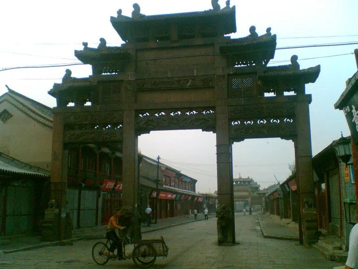 Old town street in Xingcheng with a wooden memorial archway over the road
