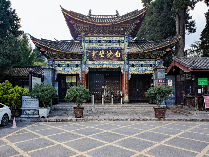Ornate painted gate marked 'Baisha Murals' with potted plants in front