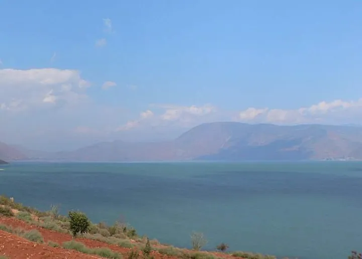 Hazy view across Chenghai Lake toward distant mountains