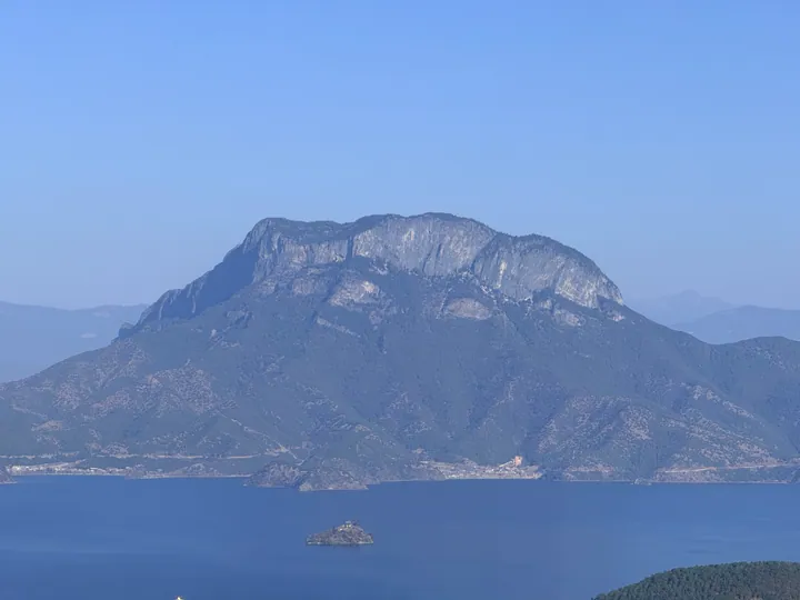 View across Lugu Lake toward the cliffs of Gemu Goddess Mountain