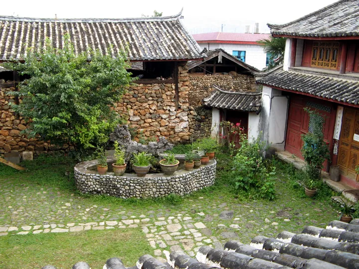 Traditional stone-walled courtyard with tiled roofs in a Naxi village