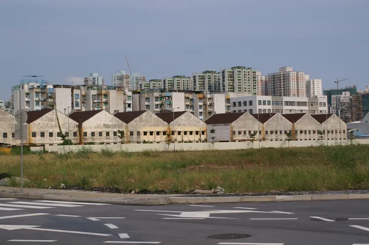 A row of old low warehouse buildings in Ilha Verde with high-rise apartment blocks in the background.