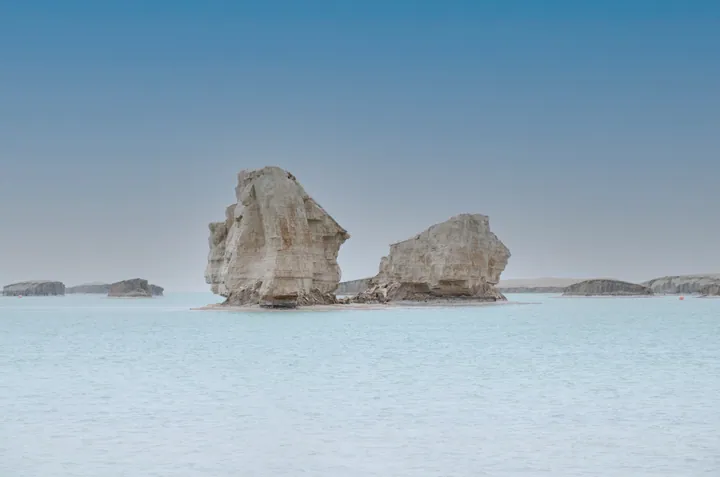 Pale eroded rock pillars surrounded by shallow blue water
