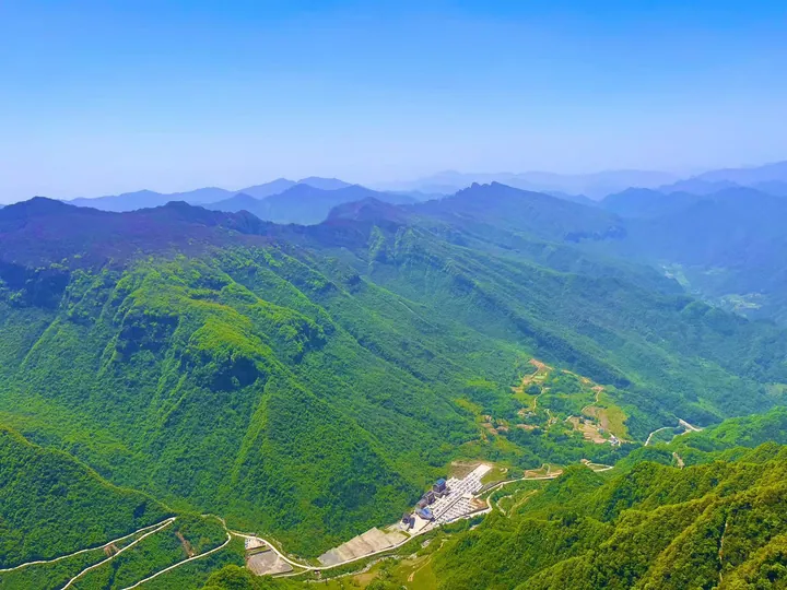 Aerial view of forested mountains and a winding resort road near Hanzhong