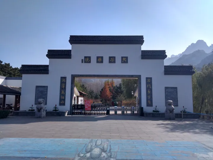 Chinese-style stone gate at the entrance to Dazhu Mountain Scenic Area, with mountain peaks visible behind