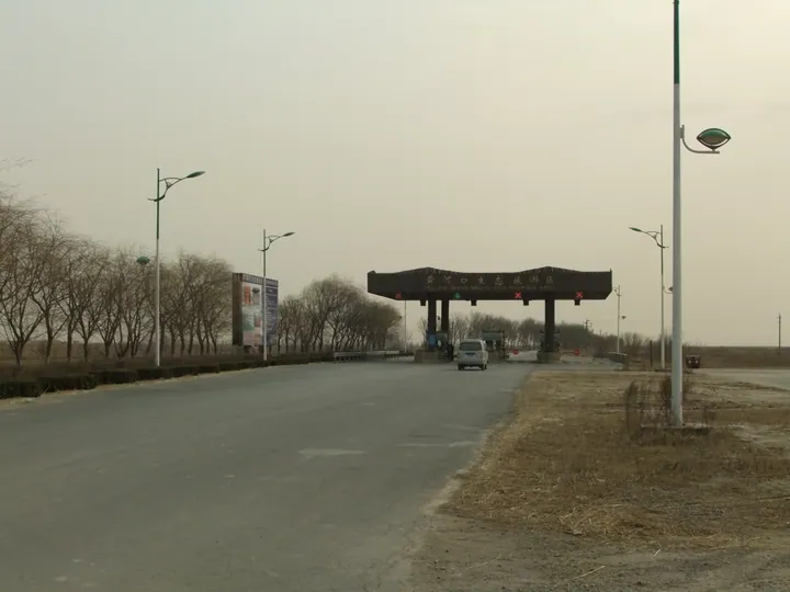 Large wooden gate structure over a road with Chinese and English signage for the Yellow River Mouth Eco-Tourism Area