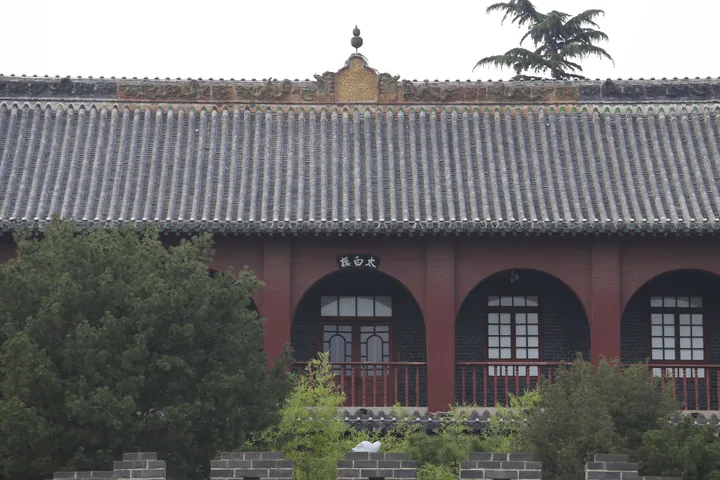 Traditional Chinese building with a grey tiled roof and arched red windows, name plaque reading Taibai Lou