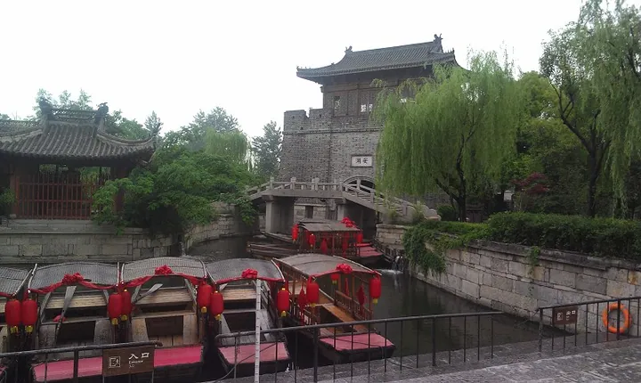 Excursion boats on the canal beneath a stone bridge and gate tower in the Old Town of Tai'erzhuang