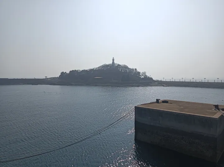 Small island with a white lighthouse in Qingdao Bay, Shinan District, Shandong