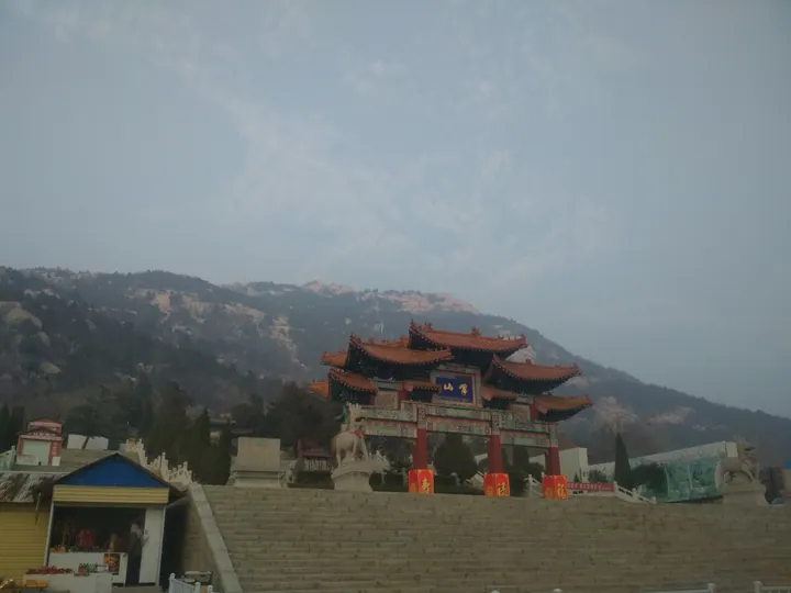 Chinese temple-style gate with the peaks of Mount Yi visible in the haze behind