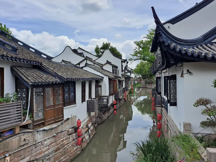 Old canal-side street with white plastered houses and hanging red lanterns