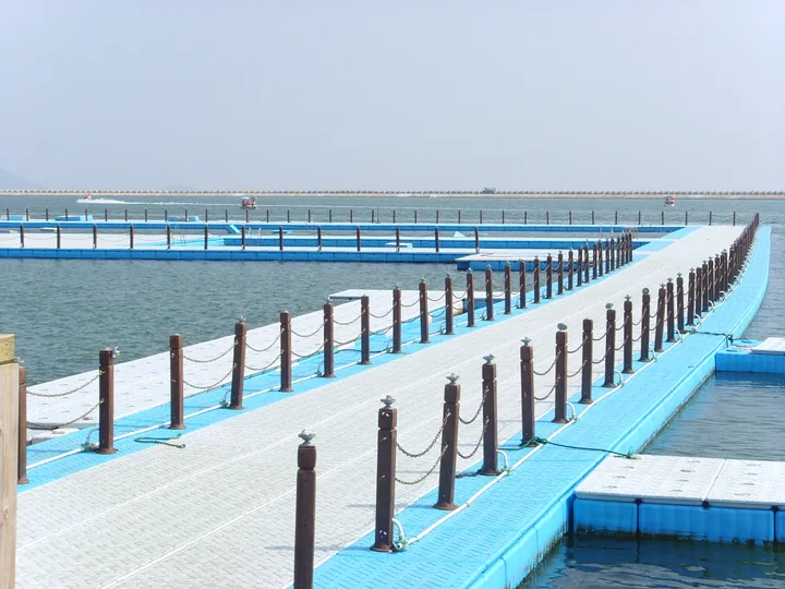 Blue floating walkway extending over a swimming enclosure in the sea