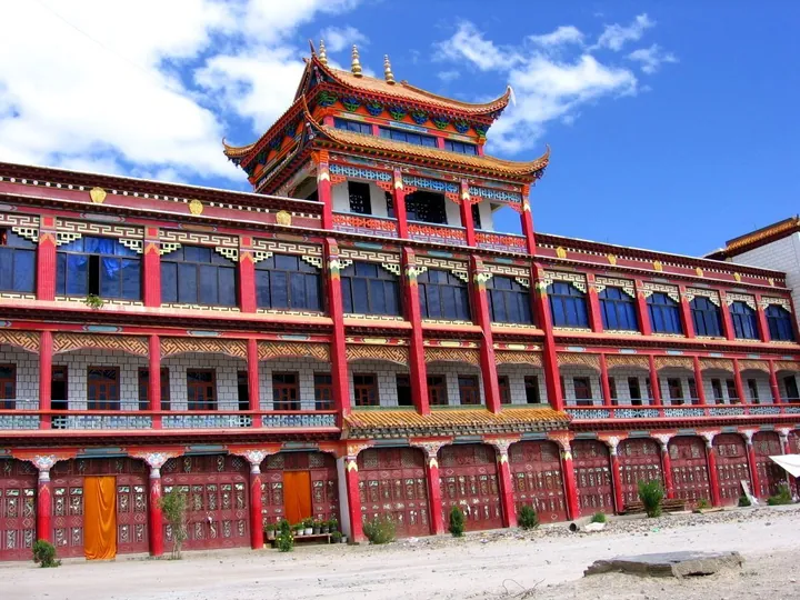 Colourfully painted multi-storey Tibetan Buddhist monastery building under a blue sky