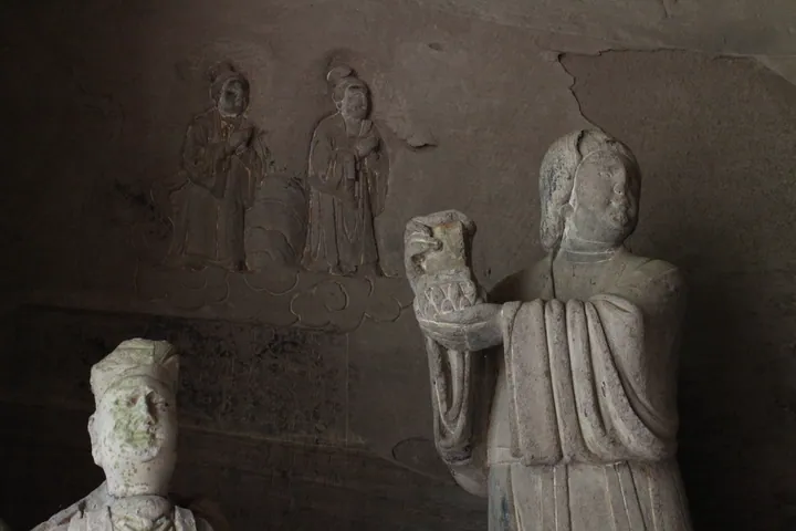 Weathered carved stone Buddhist figures and relief panels inside the Piludong grotto