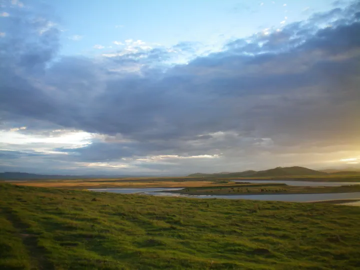 Sunset over a winding river bend across open grassland
