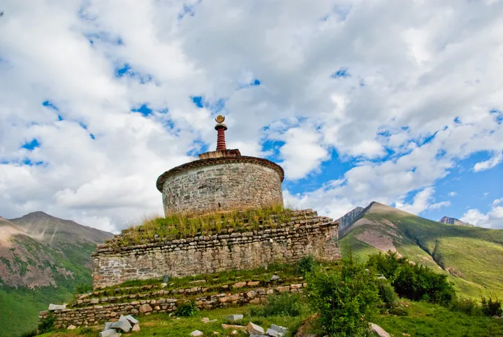 Stone Buddhist stupa on a grassy hilltop at Reting Monastery