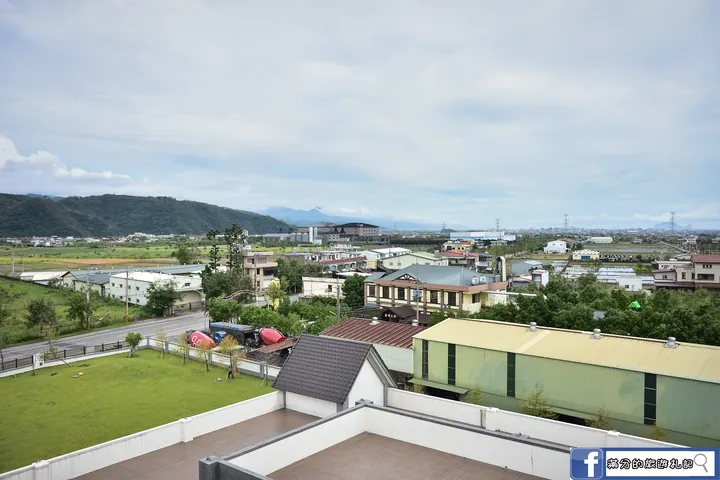 A rooftop view over fields, houses and mountains under a cloudy sky
