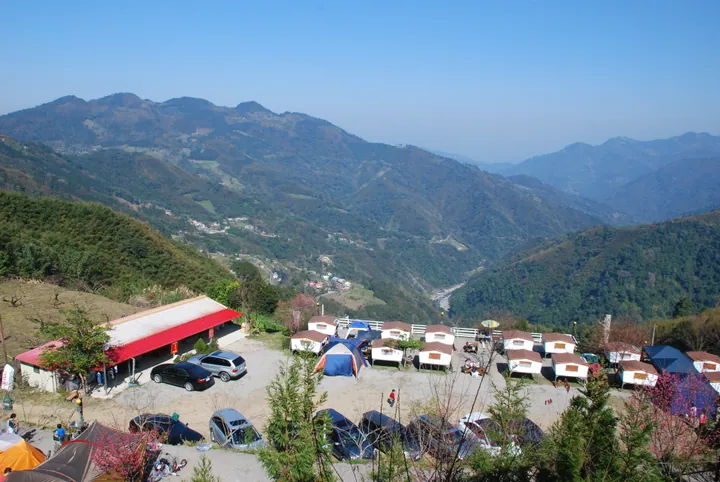 Layered green mountains with a valley and a campsite in the foreground