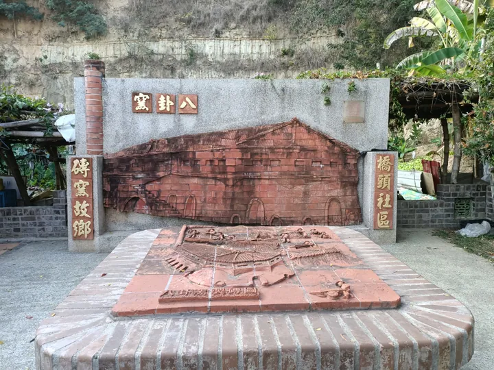 A brick relief artwork depicting a historic kiln, with a model of the kiln in front