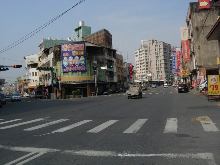 A town street intersection with shops, cars and distant hills