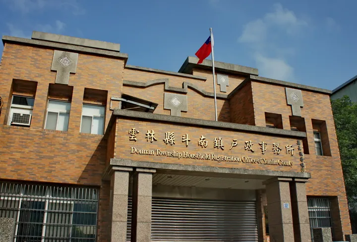 A brick civic office building with a Taiwanese flag against a blue sky