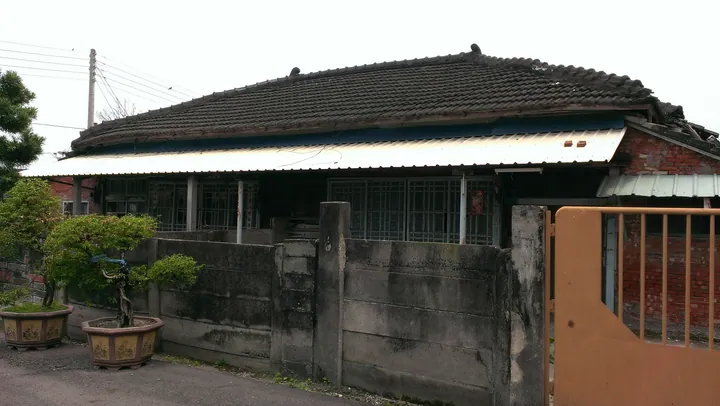 A traditional tiled-roof former school dormitory building behind a low wall