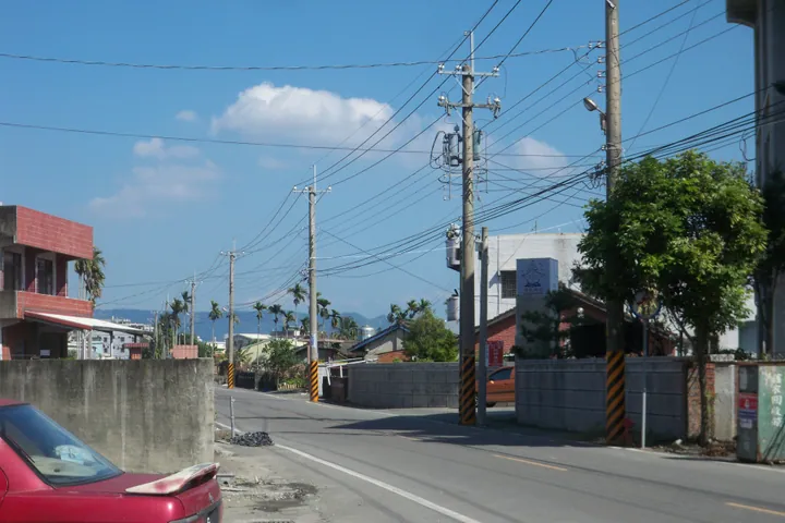 A quiet street with houses, palm trees and distant hills in Linnei Township