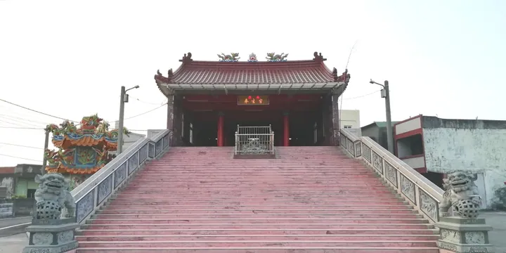 A symmetrical red temple building at the top of a wide staircase