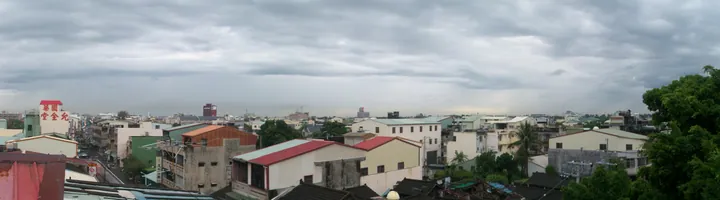 A panoramic rooftop view over a small town under dramatic clouds