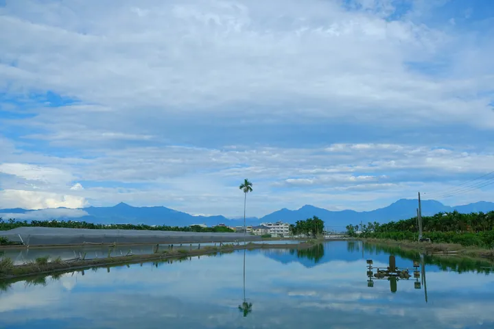 Fish pond reflecting mountains and clouds in Ligang Township