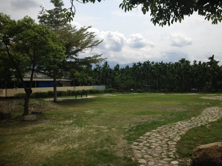 Grassy park with trees and a mountain backdrop in Gaoshu Township