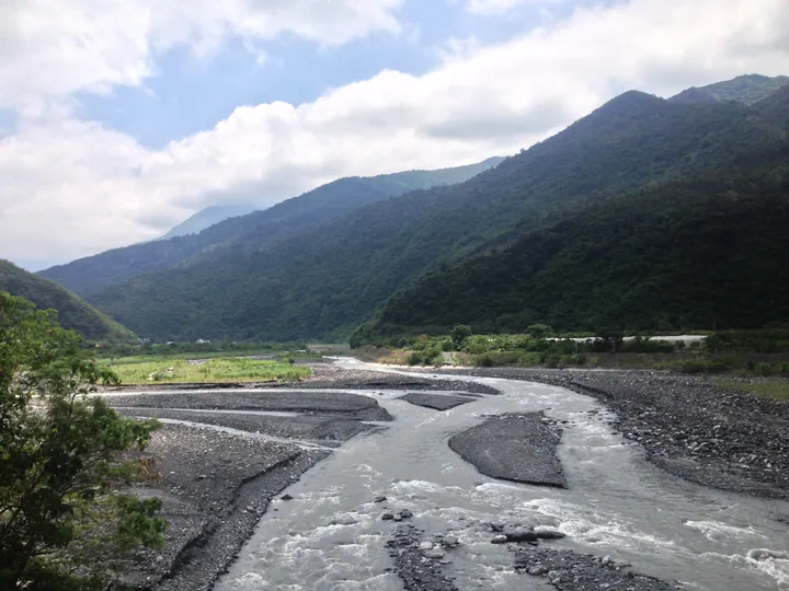 Braided gravel riverbed running through forested mountains in Laiyi Township