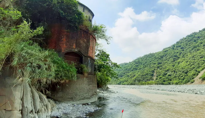 Brick irrigation intake tower beside a river amid green hills in Chunri Township