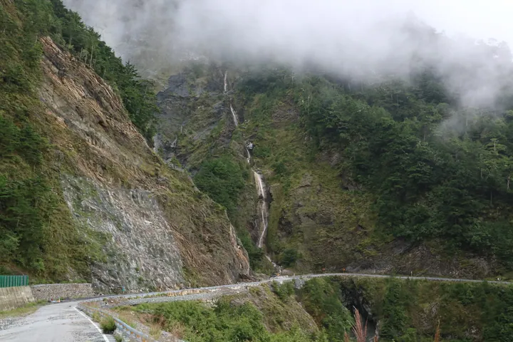 Waterfall cascading down a misty mountainside above a road in Haiduan Township