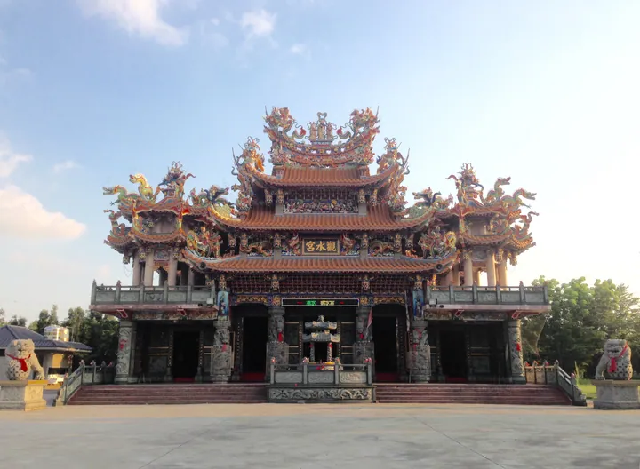 An ornately decorated Chinese temple with dragon roof ridges under a clear blue sky