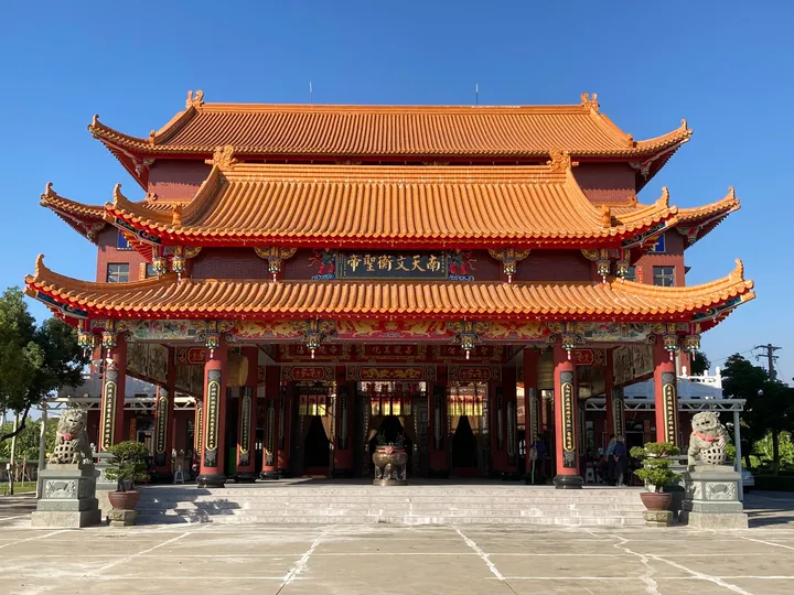 Ornate red and gold Chinese temple building with double tiered roofs under a clear blue sky in Ziguan District, Kaohsiung