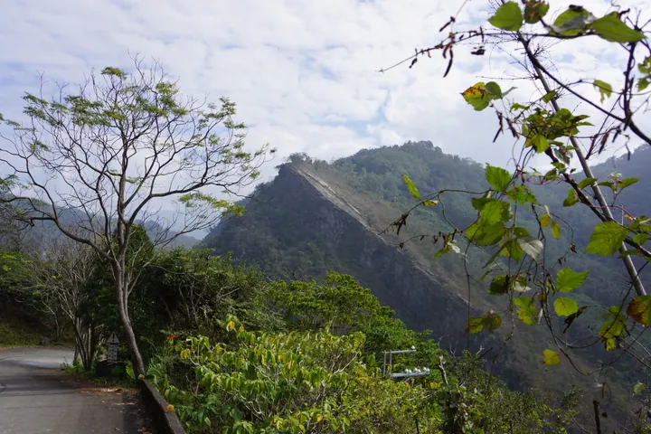 Forested mountain ridge under a partly cloudy sky in Namasia District