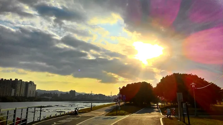 River waterfront path at sunset with a hazy city skyline in the distance, near Yonghe District, New Taipei