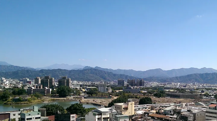 City skyline and pond with mountains in the background in Taichung