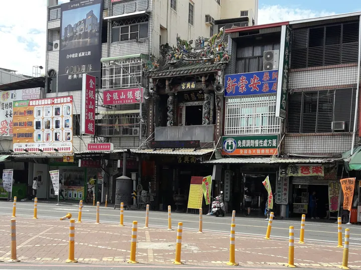 Ornate carved temple facade beside shop signage in Yanshuei District, Tainan