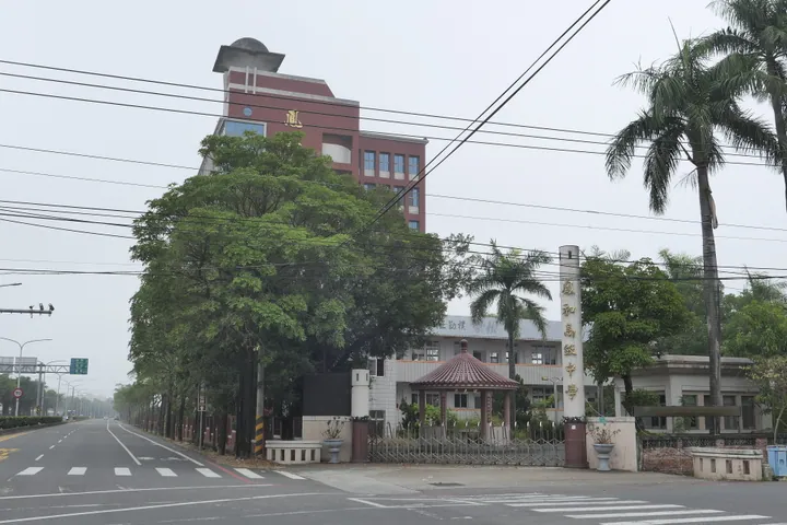 Tower-topped school building with palm trees on a street in Liouying District, Tainan