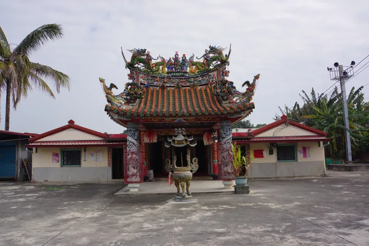Ornate temple with dragon roof and palm trees in Danei District