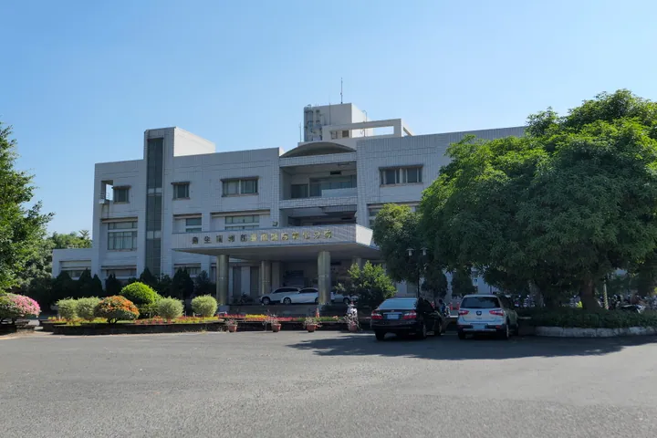 White multi-storey hospital building with parked cars and gardens in Xinhua District, Tainan