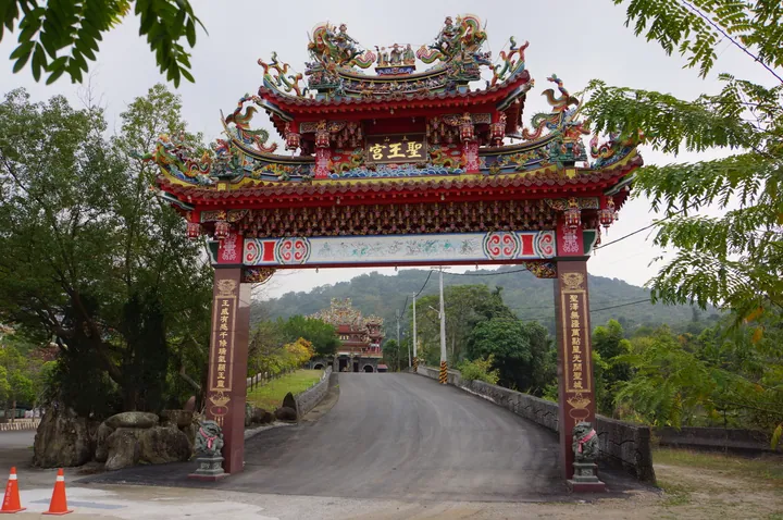 Ornate red and gold temple archway with mountains behind in Nanhua District