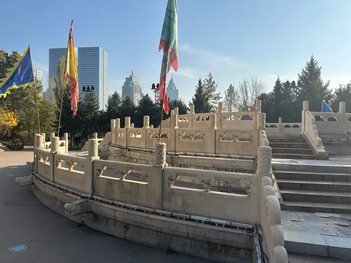 Stone balustraded terrace with flags at Hongshan Park, Ürümqi skyline in the background