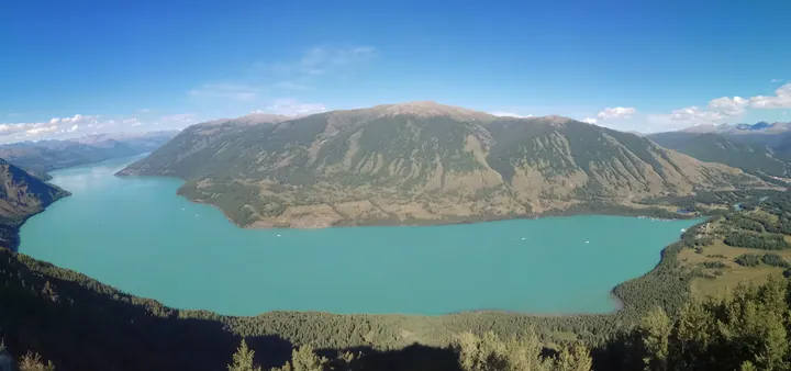 Turquoise Kanas Lake surrounded by forested mountains