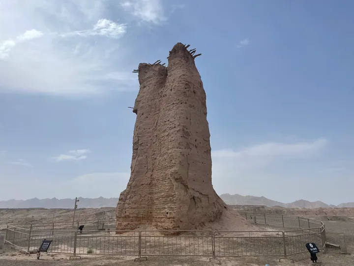 A tall weathered earthen Han-dynasty beacon tower standing in the desert near Kuqa